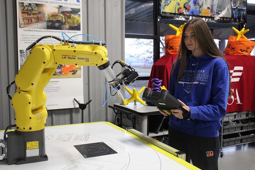 Mae Renison works with a robot in the RAMTEC lab.
