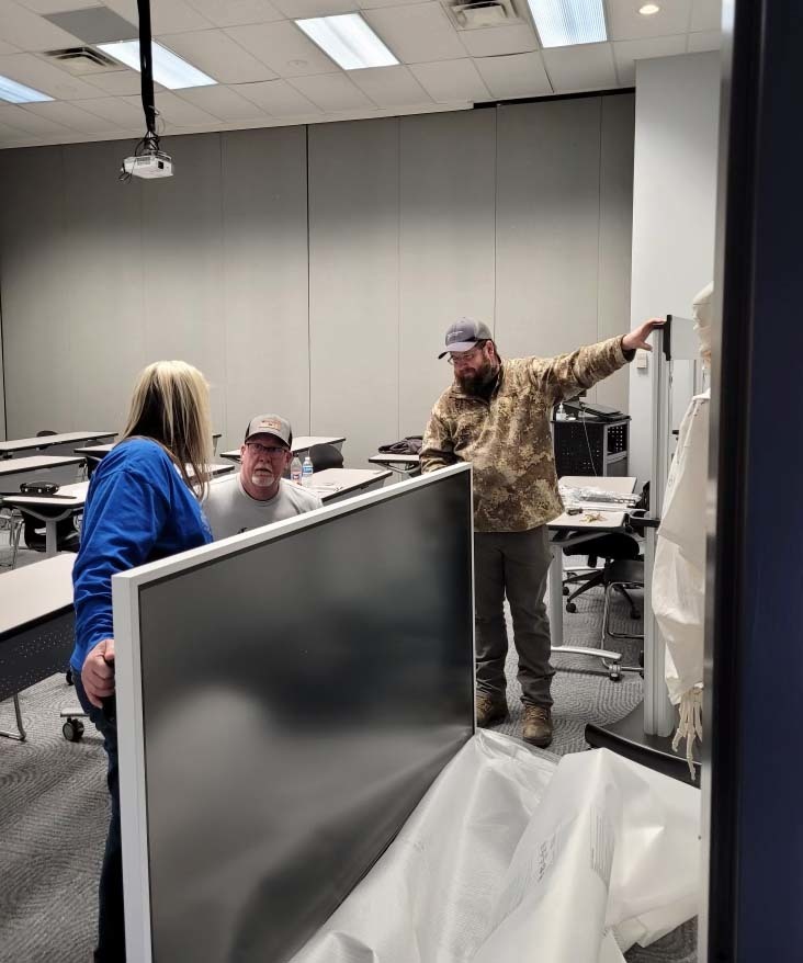 Kelly Duarte, from left, Matt Clifton and Josh Hines install one of three new  Samsung interactive displays at the Industrial Drive campus.