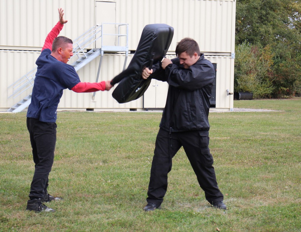 A Law & Public Safety student delivers a baton strike to a pad during a training exercise. 