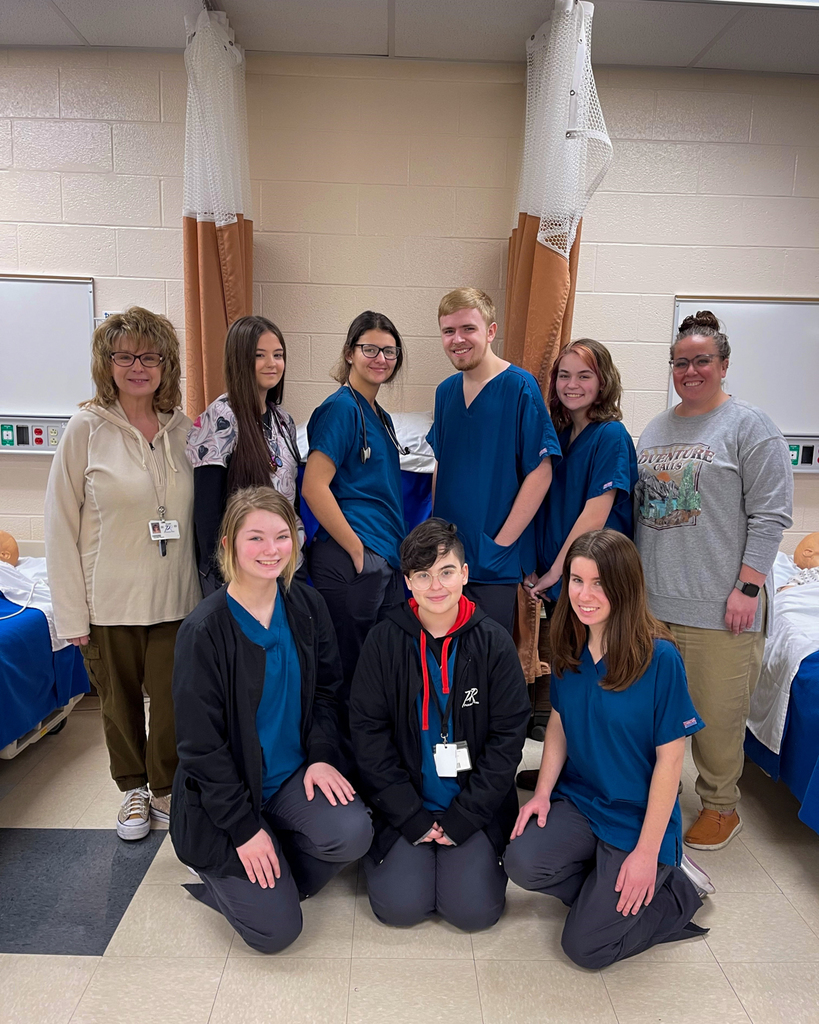 A group of students in blue scrubs pose for a photo. 