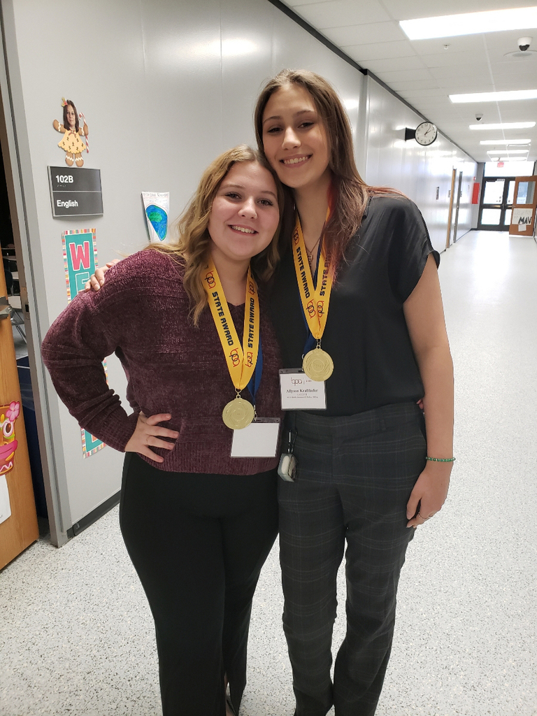 2 students pose with medals around their necks. 