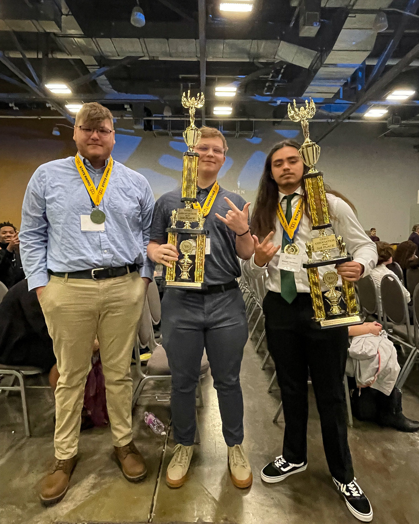 3 students pose with trophies. 