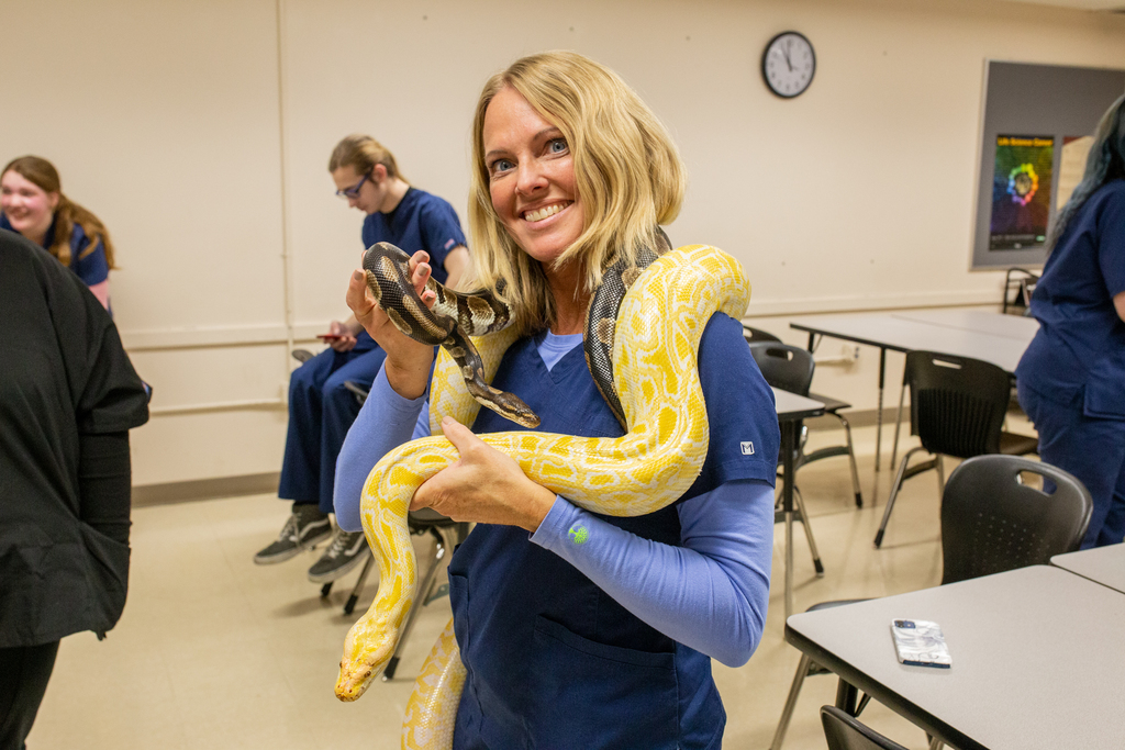 Instructor Rebecca Hopkins holds the large yellow snake and small brown snake at the same time. 