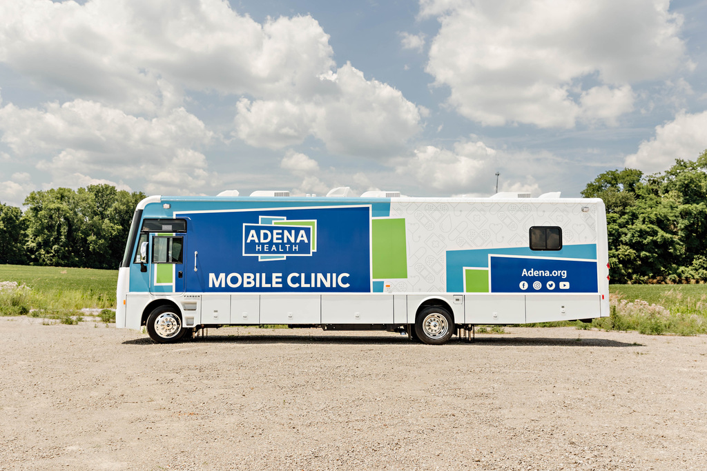 Photo of a large RV-like bus that is blue and green and says Adena Health Mobile Clinic on the side. 