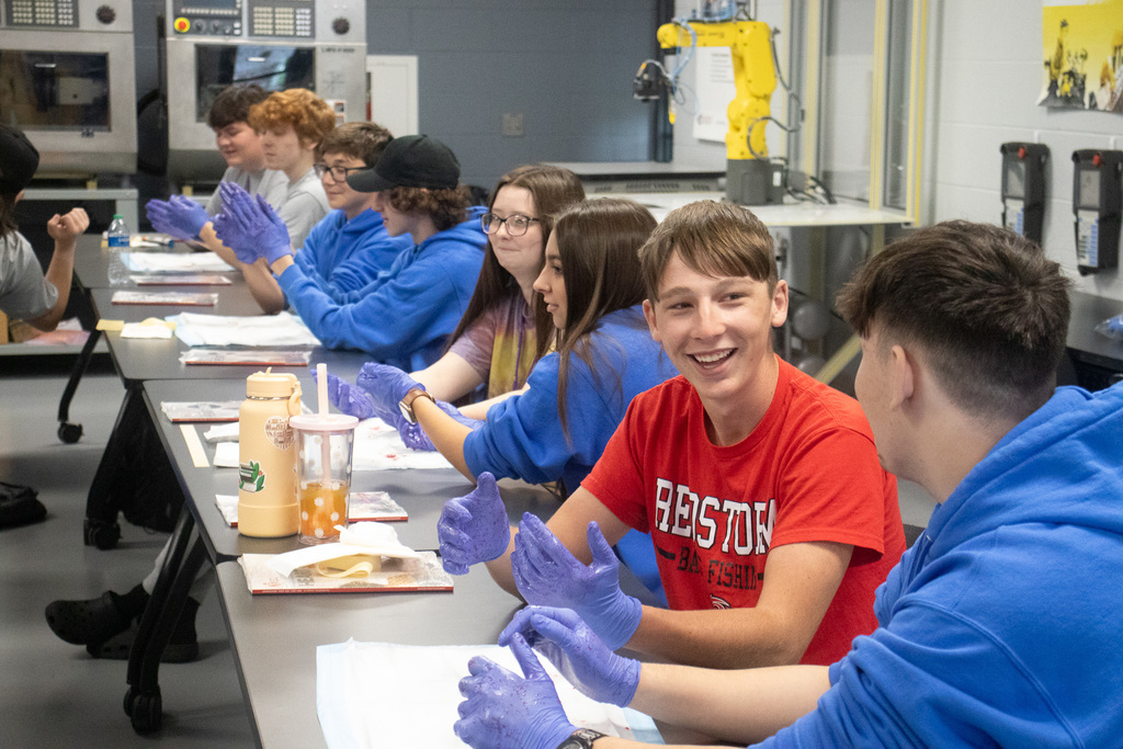 A row of students practice first aid in blue sterile gloves. 