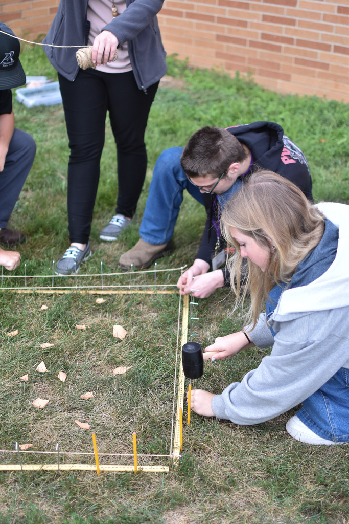 Students use a mallet to hammer stakes. 