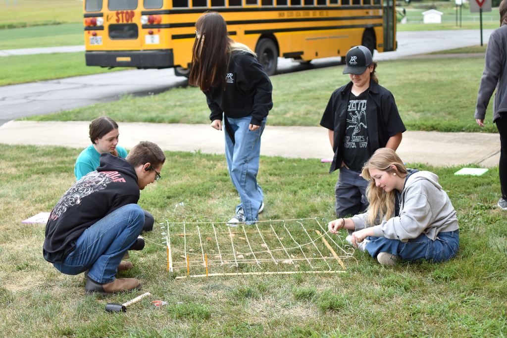 Students continue to create a grid out of stakes and string. 